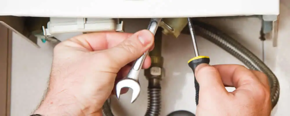 Boiler repair technician tightening pipe fittings and connections in Warwick, RI