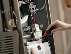 Furnace repair technician inspecting internal components and wiring in Warwick, RI