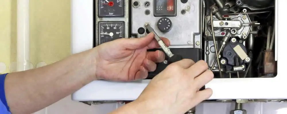 Heating repair technician adjusting boiler controls and components in Warwick, RI
