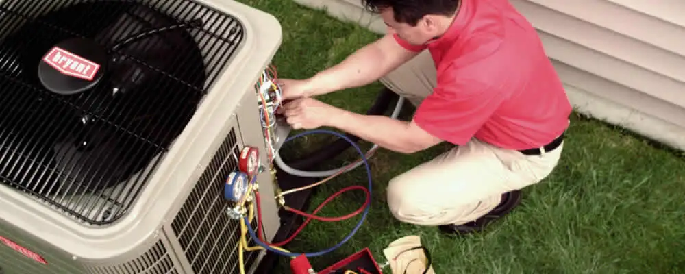 HVAC technician servicing an outdoor air conditioner unit in Warwick, RI