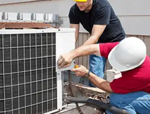 HVAC technicians repairing an outdoor AC unit on a rooftop in Warwick, RI