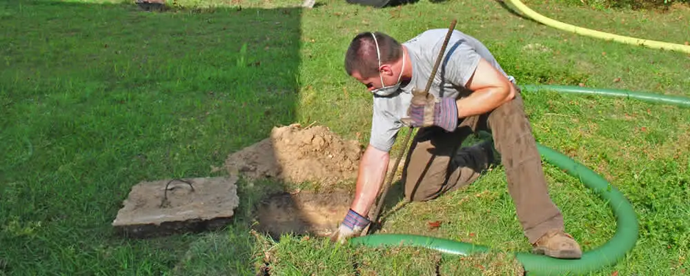 Septic pumping technician servicing a residential septic tank in Warwick, RI