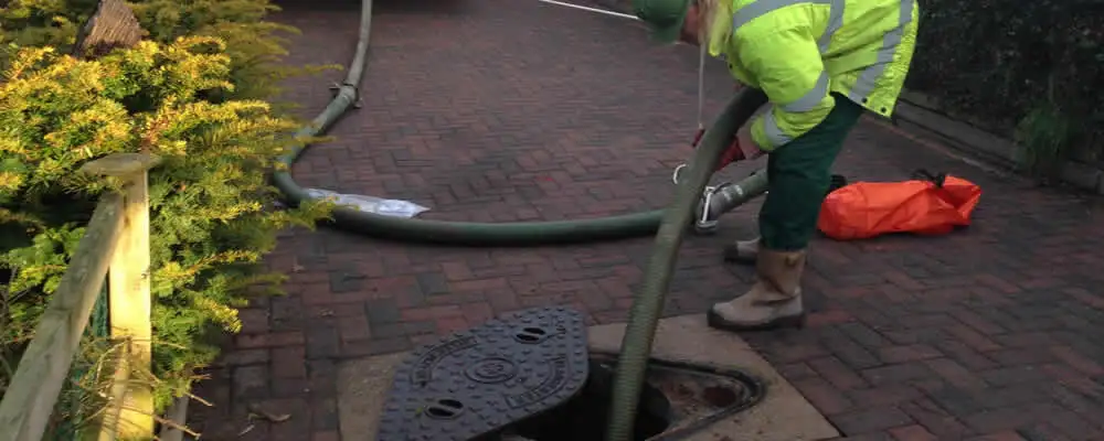 Septic tank cleaning technician servicing a septic tank with a vacuum hose in Warwick, RI