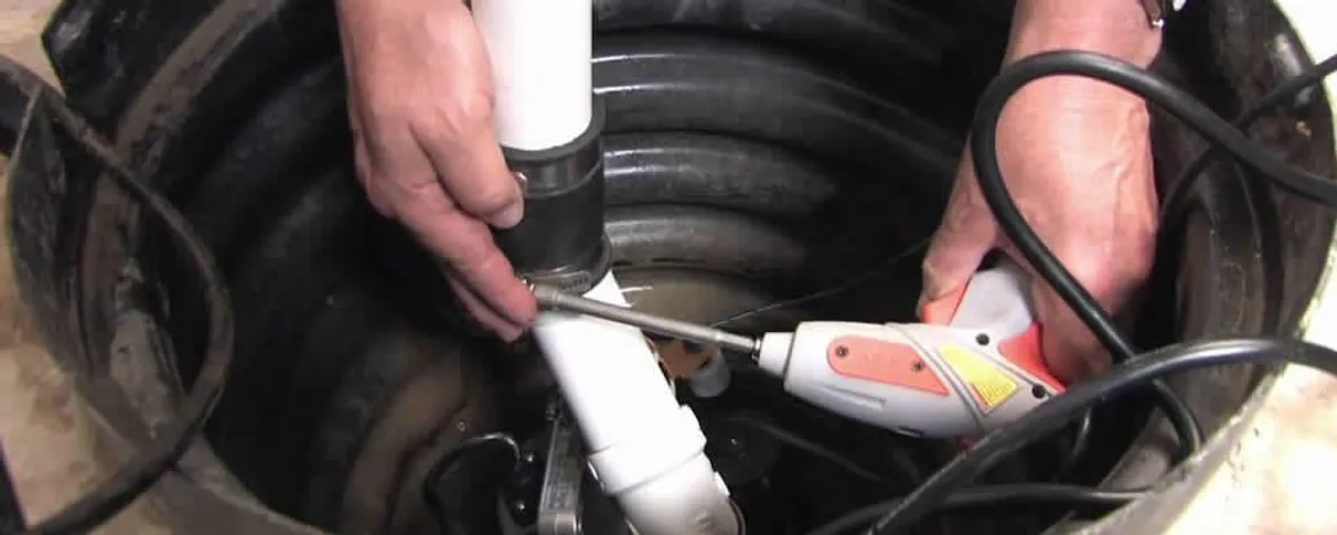 Sump pump installation technician connecting PVC discharge piping in Warwick, RI
