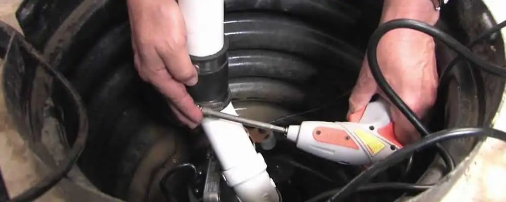 Sump pump installation technician connecting PVC discharge piping in Warwick, RI